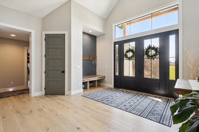 foyer entrance featuring high vaulted ceiling, wood finished floors, and baseboards