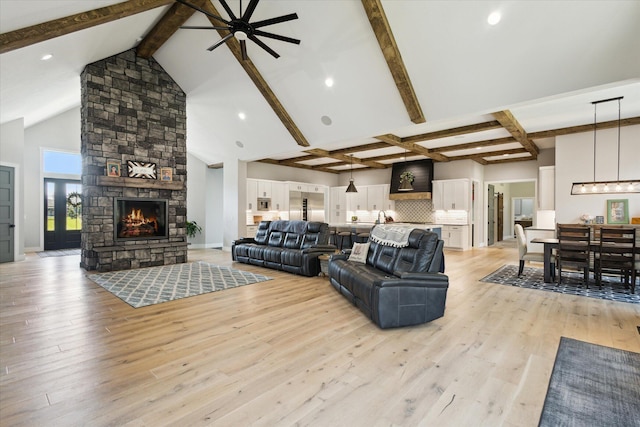 living area featuring lofted ceiling with beams, recessed lighting, light wood finished floors, a fireplace, and a ceiling fan