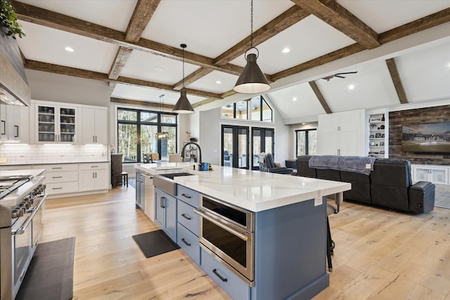kitchen featuring a sink, backsplash, pendant lighting, white cabinets, and appliances with stainless steel finishes