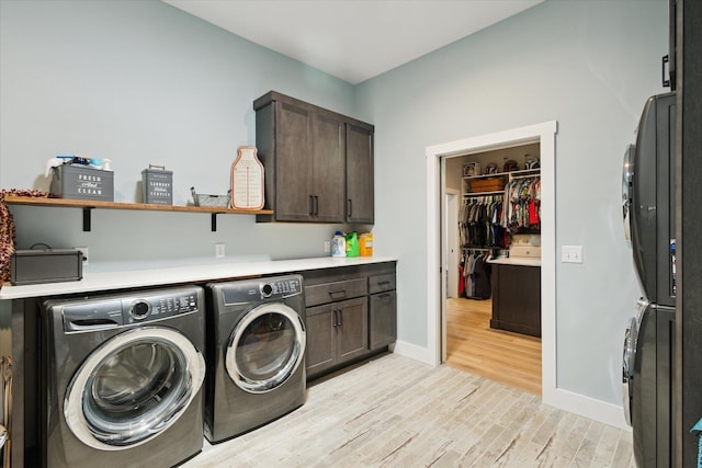 washroom featuring light wood finished floors, baseboards, cabinet space, and washing machine and dryer