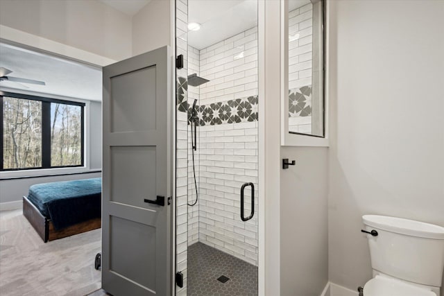 bathroom featuring toilet, connected bathroom, a stall shower, and baseboards