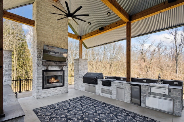 view of patio featuring ceiling fan, an outdoor stone fireplace, an outdoor kitchen, and a grill