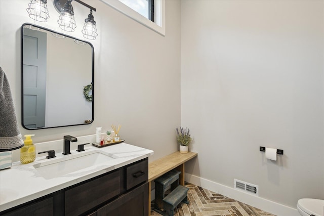 bathroom featuring toilet, visible vents, vanity, and baseboards