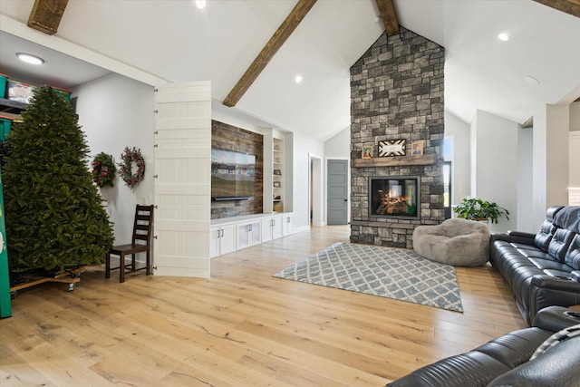 living area featuring built in shelves, wood finished floors, a fireplace, and vaulted ceiling with beams