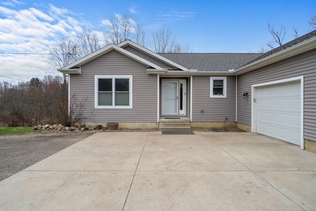 single story home featuring a shingled roof, a garage, and concrete driveway