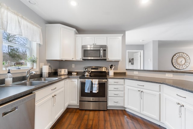 kitchen featuring a sink, dark countertops, recessed lighting, white cabinetry, and stainless steel appliances