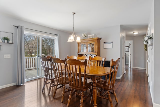 dining area featuring dark wood-type flooring, an inviting chandelier, and baseboards