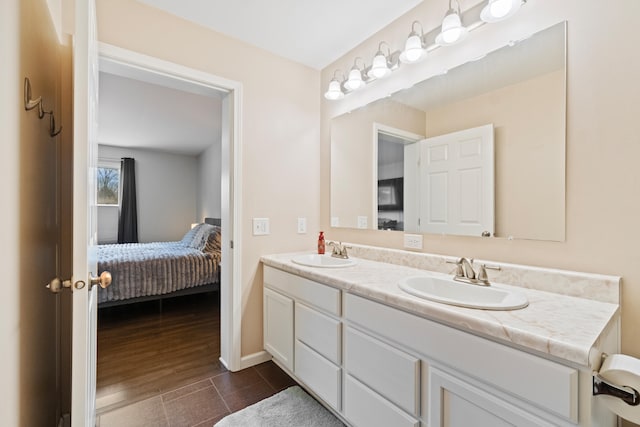 ensuite bathroom featuring a sink, ensuite bathroom, baseboards, and double vanity