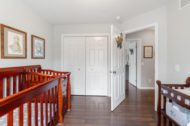 bedroom featuring dark wood finished floors, a nursery area, a closet, visible vents, and baseboards