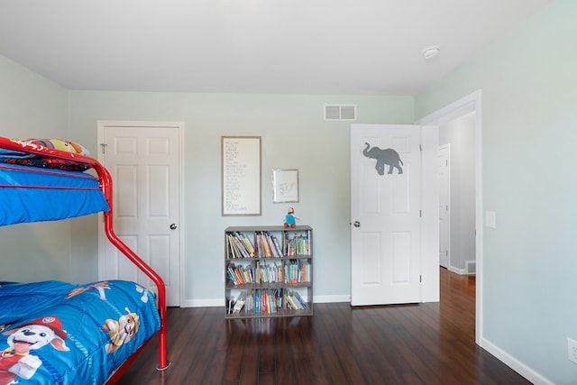 bedroom with visible vents, baseboards, and wood finished floors