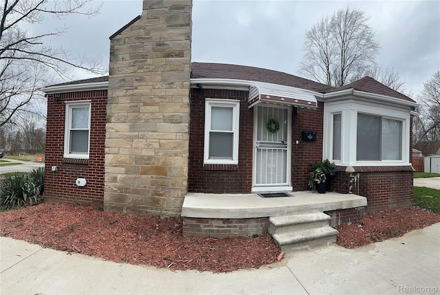 6134 Woodhall St, Detroit, MI 48224 - view of front of home with a chimney, brick siding, and a shingled roof