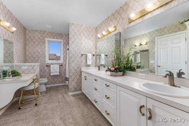 bathroom with toilet, double vanity, a sink, and baseboards