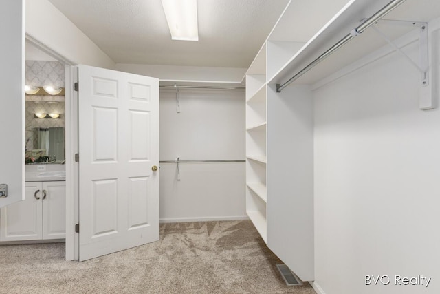 walk in closet with visible vents and light colored carpet