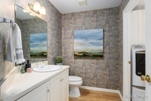 bathroom featuring washer / clothes dryer, vanity, toilet, visible vents, and wood finished floors