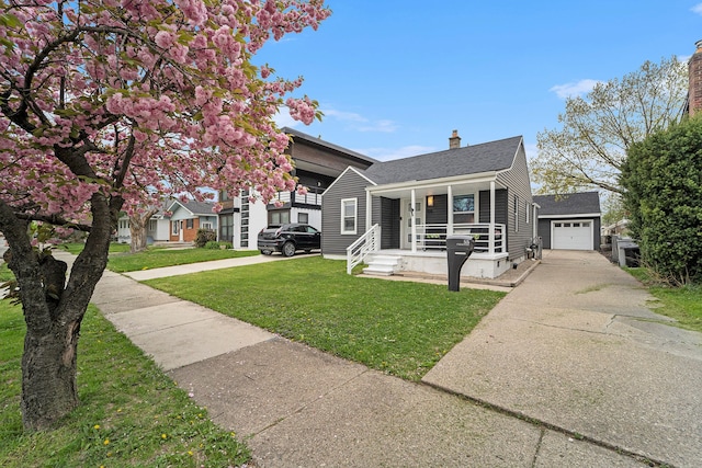 bungalow featuring a porch, driveway, a chimney, a front yard, and a detached garage