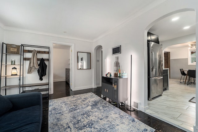 living room with crown molding, arched walkways, and baseboards