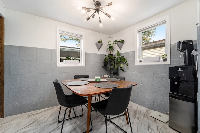 dining area featuring tile walls, wainscoting, and marble finish floor