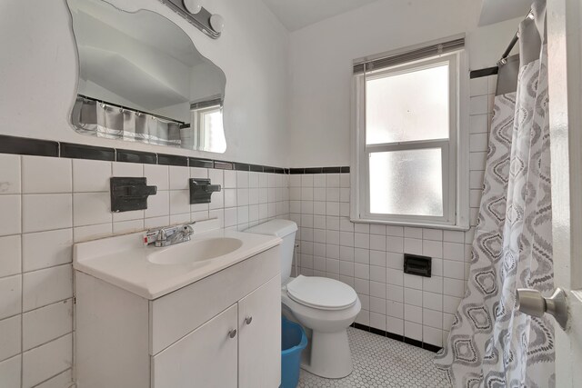 19544 Strasburg St, Detroit, MI 48205 - bathroom with vanity, toilet, wainscoting, tile walls, and tile patterned floors