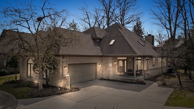view of front of property with concrete driveway, roof with shingles, a chimney, an attached garage, and central AC