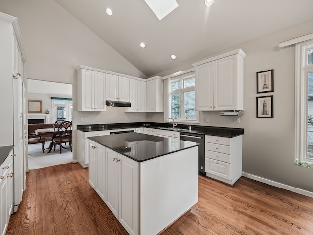 kitchen featuring dishwasher, dark countertops, light wood-style floors, under cabinet range hood, and white cabinetry
