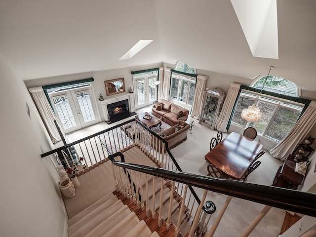 stairs with plenty of natural light, carpet flooring, french doors, and a warm lit fireplace