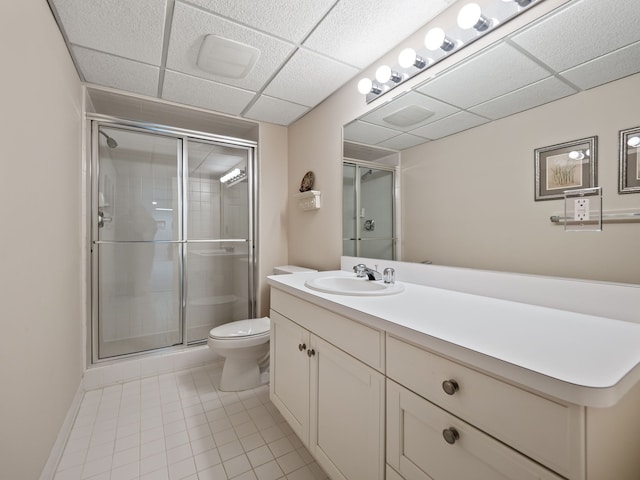 bathroom featuring vanity, a drop ceiling, toilet, a stall shower, and tile patterned floors