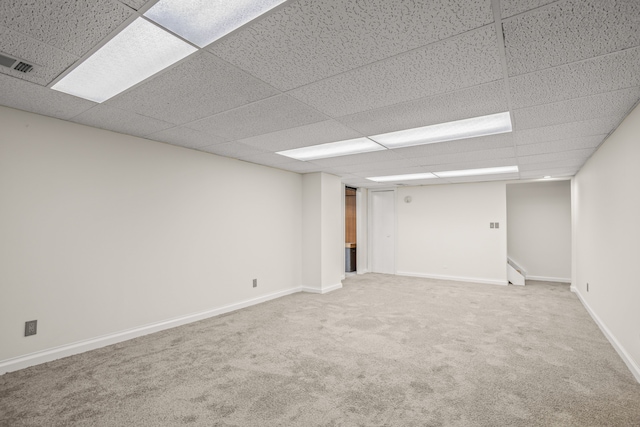 finished below grade area with carpet, a paneled ceiling, baseboards, and visible vents