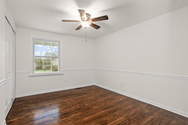 empty room featuring dark wood-type flooring, baseboards, a ceiling fan, and visible vents