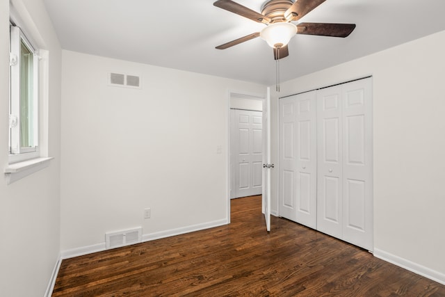 unfurnished bedroom with a closet, baseboards, dark wood finished floors, and visible vents
