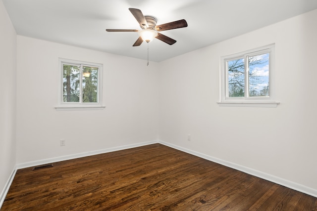 empty room with dark wood finished floors, baseboards, and a healthy amount of sunlight