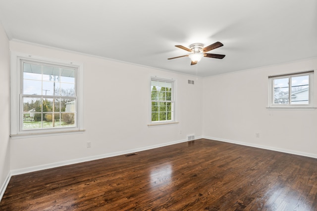 spare room featuring dark wood-type flooring, visible vents, a ceiling fan, and ornamental molding