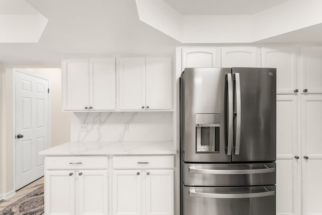 kitchen with white cabinetry, light stone countertops, and stainless steel refrigerator with ice dispenser