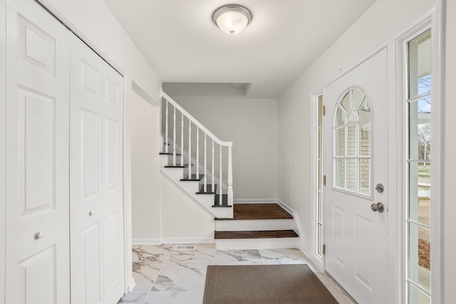 foyer entrance with marble finish floor, baseboards, visible vents, and stairs