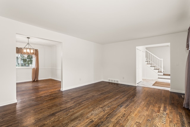 unfurnished living room with visible vents, stairs, baseboards, dark wood-style floors, and a notable chandelier