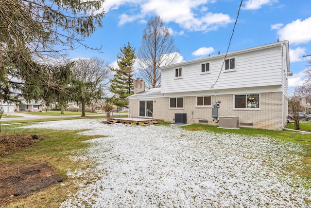 back of house with brick siding, central air condition unit, a wooden deck, and a chimney