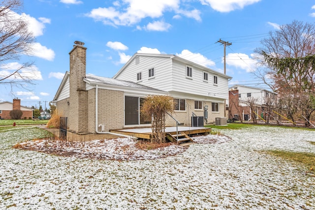back of property with a deck, a chimney, central AC unit, and brick siding