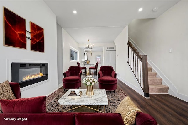 11393 Fisher Ave, Warren, MI 48089 - living room with stairs, wood finished floors, a glass covered fireplace, baseboards, and a notable chandelier