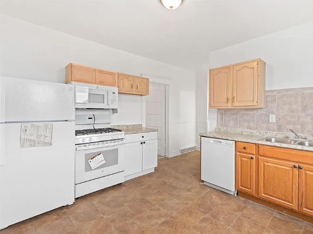 kitchen with visible vents, light brown cabinets, a sink, white appliances, and light stone countertops