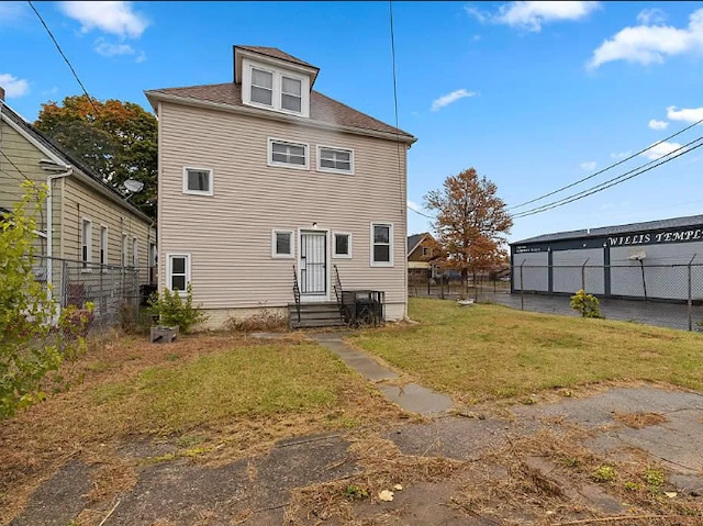 rear view of house with fence and a lawn