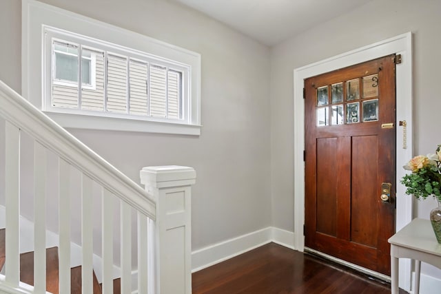 foyer entrance with dark wood-type flooring, baseboards, plenty of natural light, and stairs