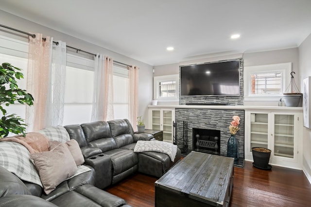 living room featuring recessed lighting, a stone fireplace, and dark wood finished floors