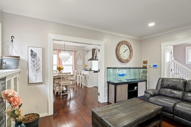 living area featuring dark wood-style flooring, baseboards, a notable chandelier, and stairs