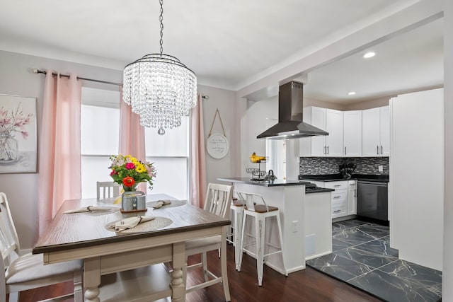 kitchen with white cabinetry, dishwasher, dark countertops, island range hood, and a notable chandelier