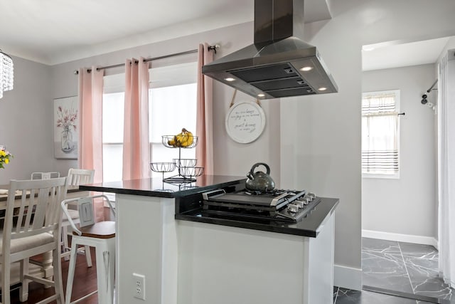kitchen featuring baseboards, dark countertops, marble finish floor, a breakfast bar area, and extractor fan