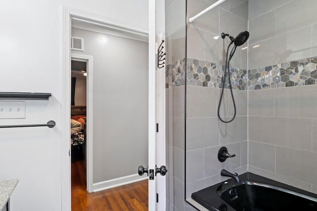 bathroom featuring shower / bathtub combination, wood finished floors, baseboards, and visible vents