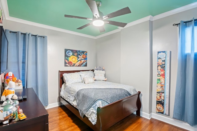 bedroom with baseboards, crown molding, and wood finished floors