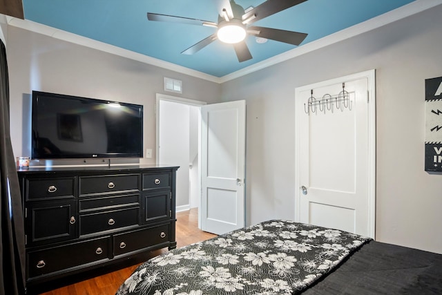 bedroom with crown molding, visible vents, a ceiling fan, and wood finished floors