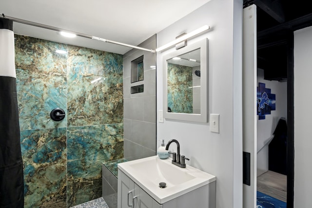 full bathroom featuring a tile shower and vanity