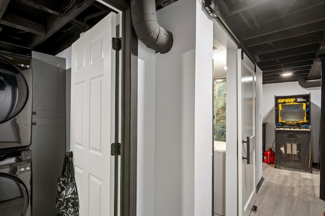 washroom with stacked washer / dryer, laundry area, and light wood finished floors