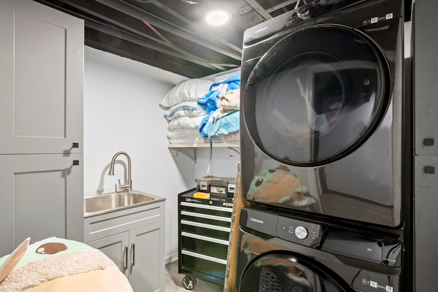 laundry room featuring stacked washer and clothes dryer, a sink, and cabinet space